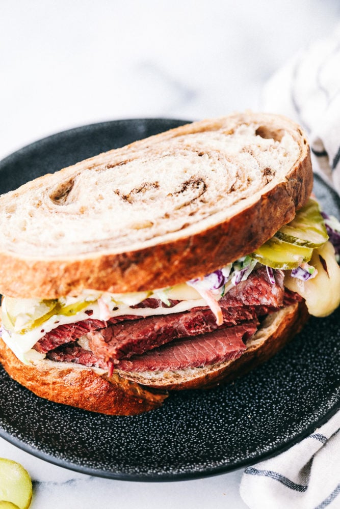This corned beef sandwich is packed with so much flavor from the thick slices of corned beef layered with all the favorite toppings making this sandwich irresistible. Leftover corned beef for the WIN!ย A corned beef sandwich on a plate.