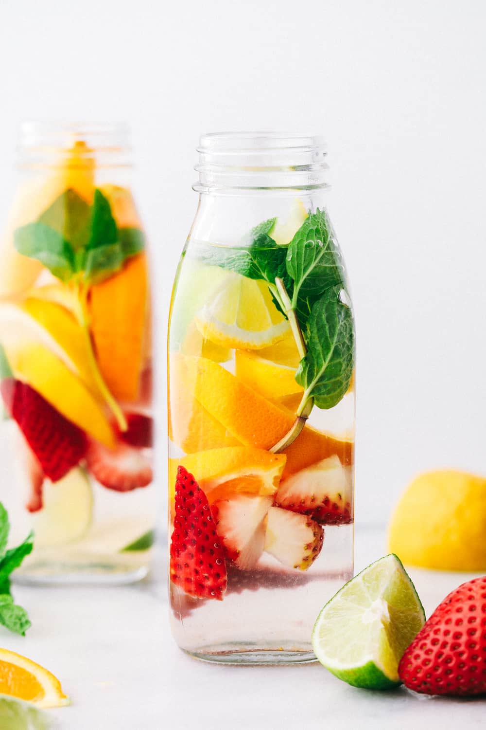 Detox Water is a naturally flavored water mixed with sliced oranges,ย citrus filled lemons and limes, fresh strawberries and garnished with mint making this anย irresistibleย water. Only 5 Minutes to make!ย Detox water in a glass jar filled with lemon, limes, strawberries and mint.