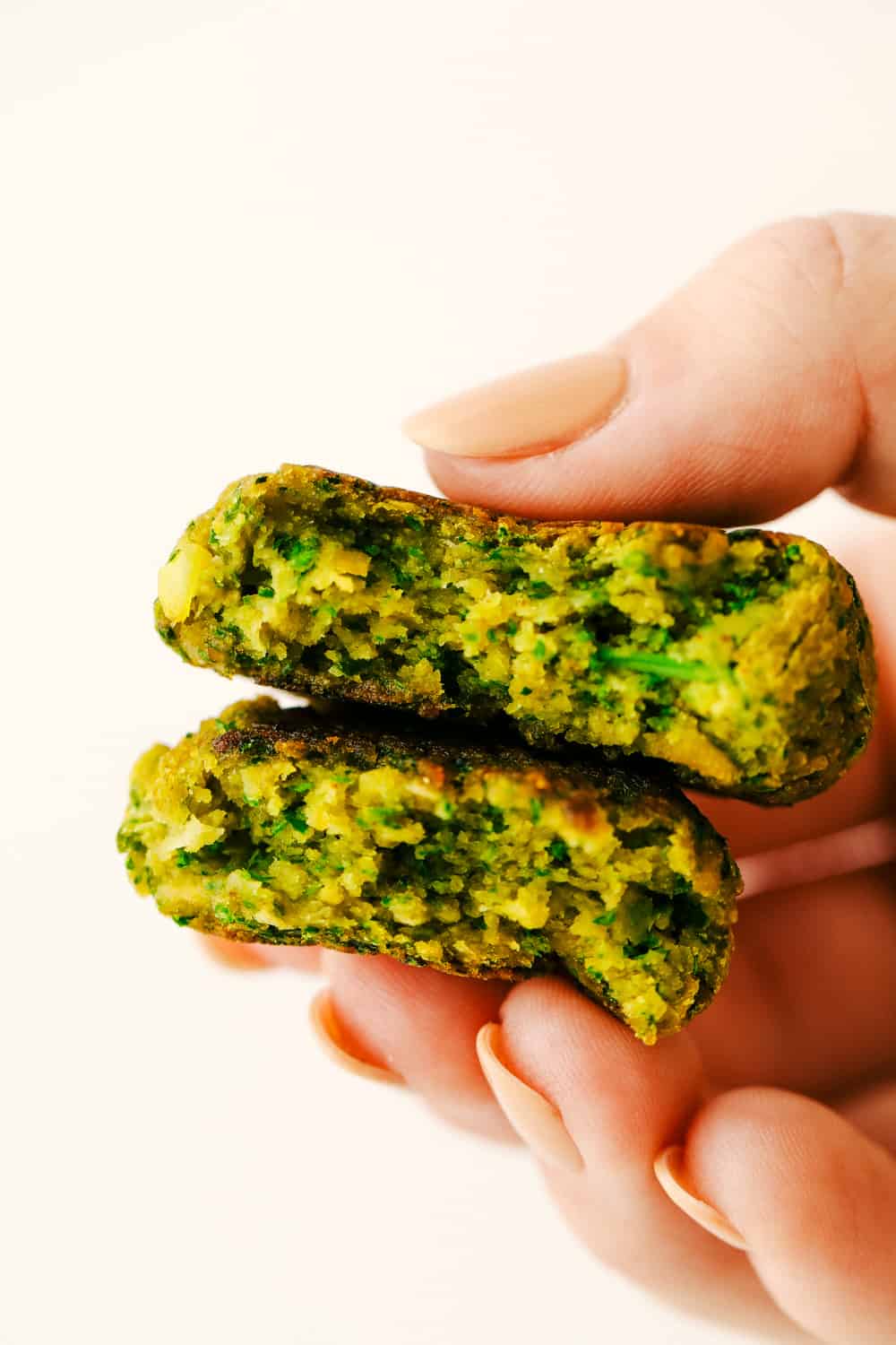 Falafel is a round bite sized mixture of garbanzo beans, seasonings and a hint of spice from a jalapeño all cooked and ready to add to any wrap or salad. A healthy little bite! Two falafel stacked on top of each other with someone holding them.