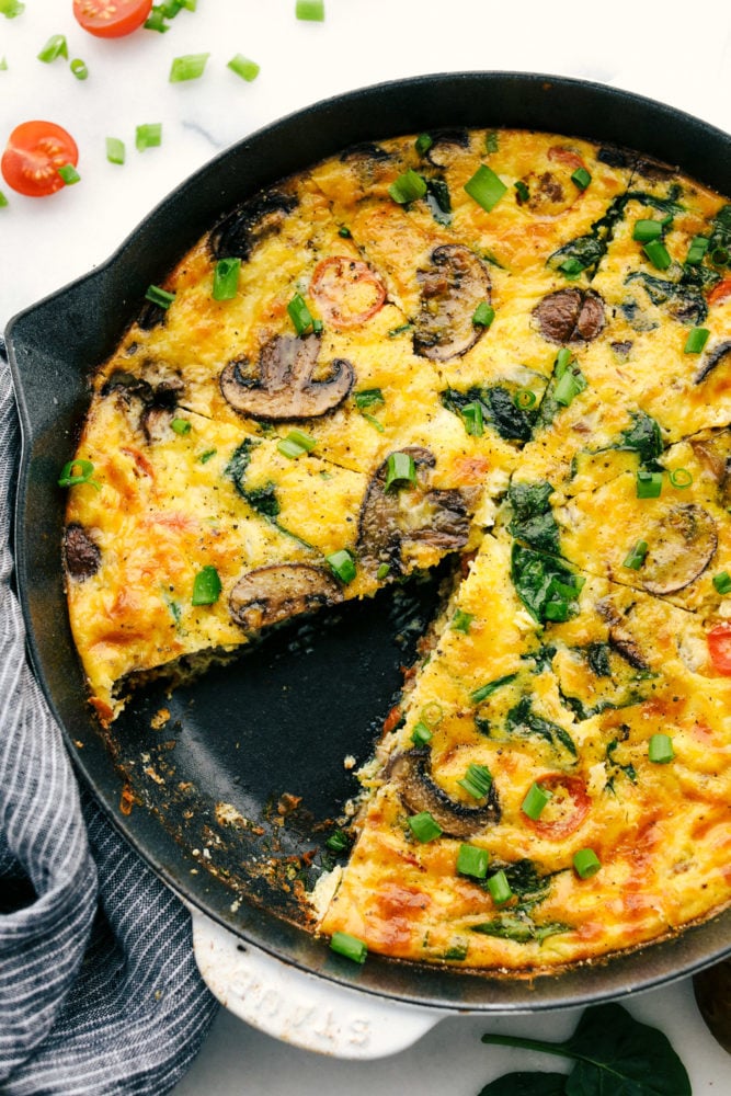 This breakfast frittata is filled with chunks of sausage, slices of mushrooms and sweet tomatoes making this a breakfast everyone will love. So simple to make and full of so much flavor! Breakfast frittata cooked on a skillet with a slice of frittata missing from it.