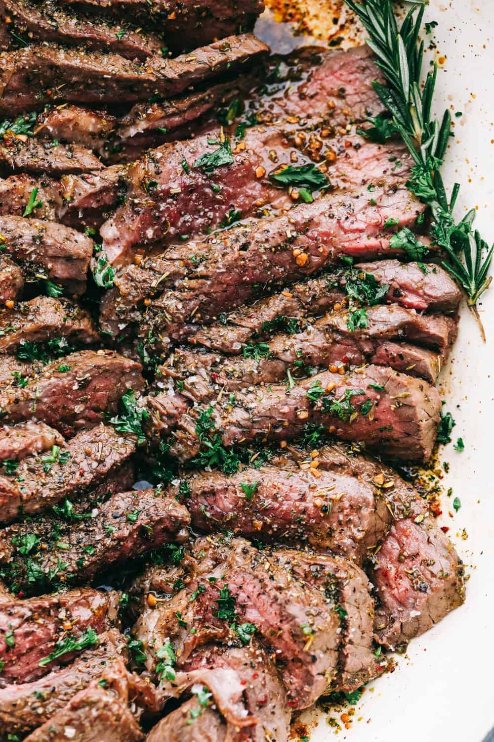 London Broil is a perfectly tender piece of meat after being marinated in a liquid mixture with spices and seasoning then broiled in the oven. A decadent dinner made easy! London Broil sliced on a platter.