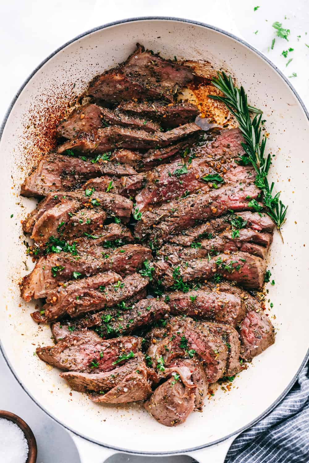 London Broil is a perfectly tender piece of meat after being marinated in a liquid mixture with spices and seasoning then broiled in the oven. A decadent dinner made easy! London Broil cut in slices plated on a white plate.