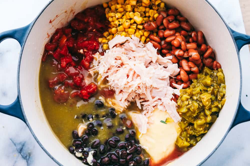 You are going to fall in love with this quick and easy 8 Can Chicken Taco Soup recipe! It is the perfect dinner when there is no time to run to the grocery store but the family needs dinner, like, NOW. Grab these ingredients right out of your pantry and whip up a delicious and flavorful soup! All the cans of beans, corn, chicken and enchilada sauce in the pot with cream of chicken soup and chicken broth.