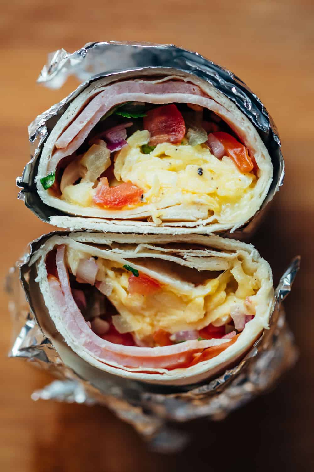 These breakfast burritos are freezer friendly and stuffed with scrambled eggs, deli ham, pico de gallo and plenty of cheese. Breakfast burritos packed in foil