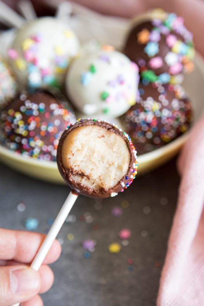 Cake Pops are the cutest desserts for any celebratory occasions. These pretty cake pops are made with vanilla cake mixed with cream cheese frosting, covered with melted chocolate and festive sprinkles. A half eaten cake pop