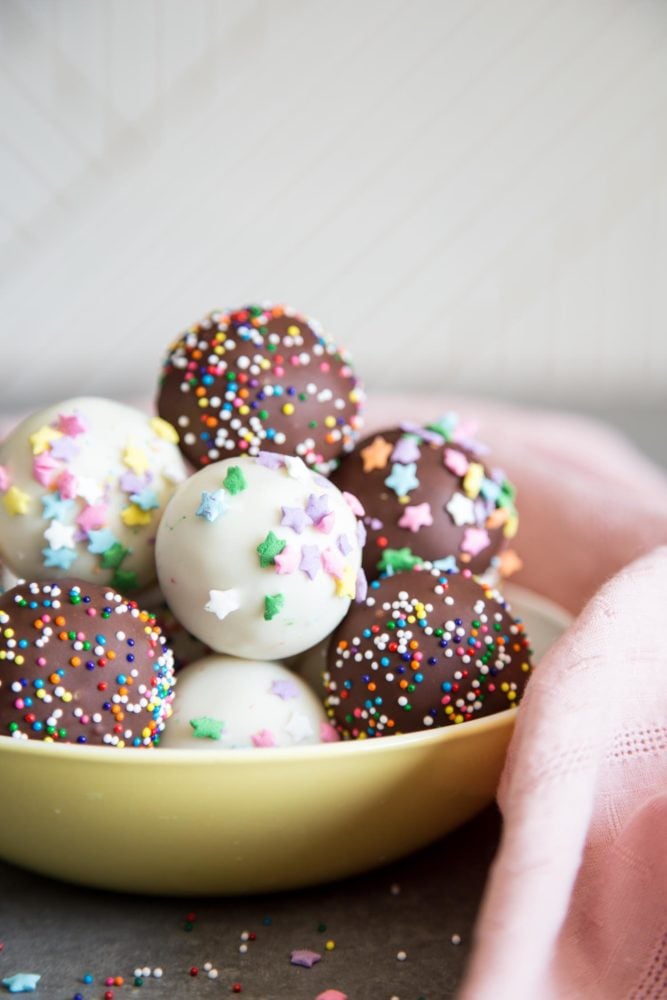 Cake Pops are the cutest desserts for any celebratory occasions. These pretty cake pops are made with vanilla cake mixed with cream cheese frosting, covered with melted chocolate and festive sprinkles. Cake pops in a bowl
