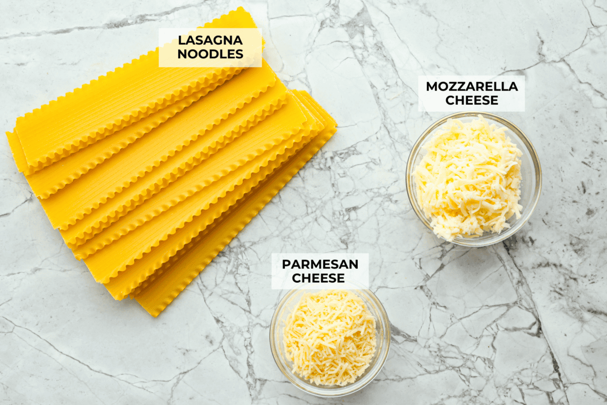 These Lasagna roll-ups have all the flavors of a classic lasagna wrapped up in a fun lasagna twist! This recipe is an easier approach to this classic Italian comfort food; seasoned beef, sweet marinara sauce, and melty, creamy cheese wrapped in a perfectly al dente noodle. Overhead shot of labeled rollup ingredients.