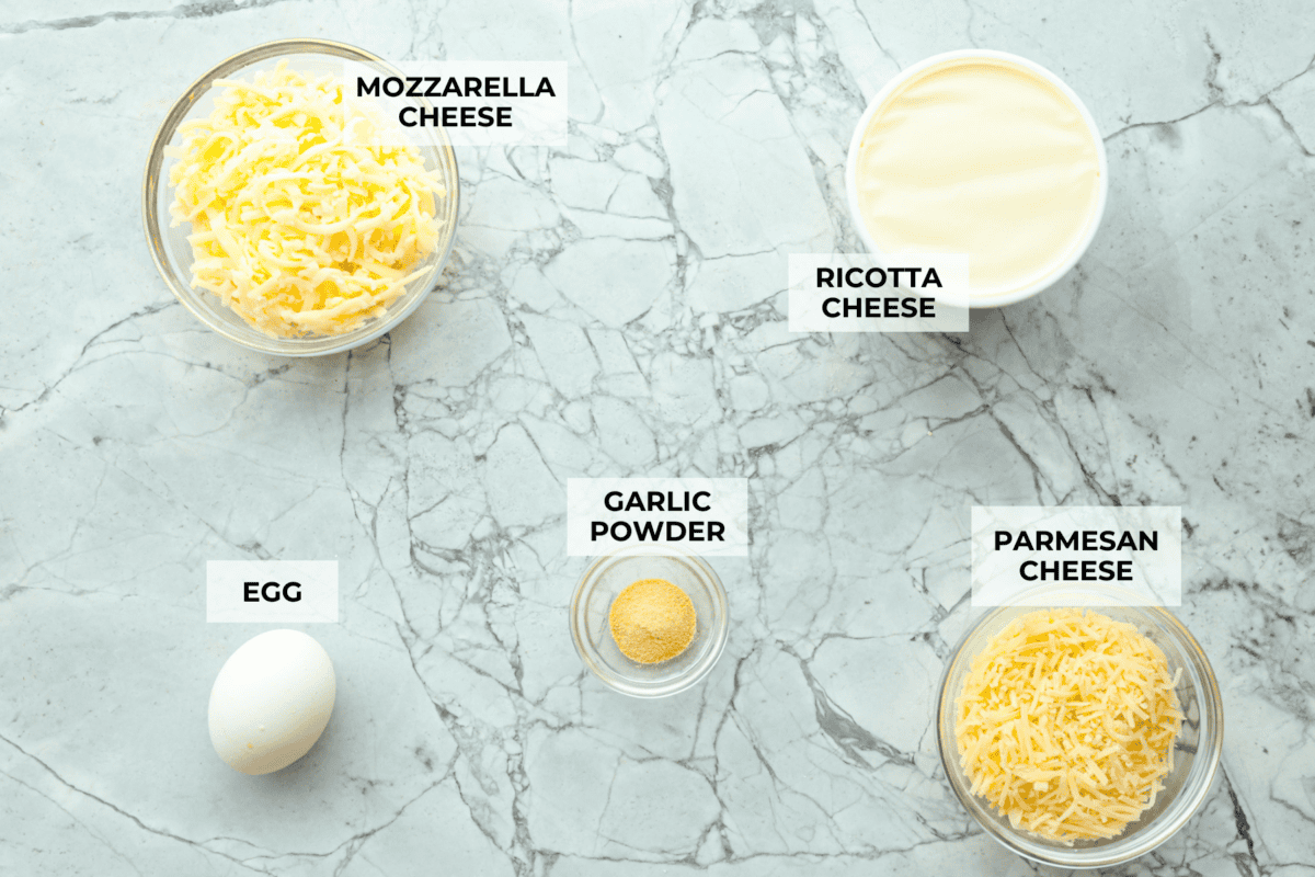 These Lasagna roll-ups have all the flavors of a classic lasagna wrapped up in a fun lasagna twist! This recipe is an easier approach to this classic Italian comfort food; seasoned beef, sweet marinara sauce, and melty, creamy cheese wrapped in a perfectly al dente noodle. Overhead shot of labeled cheese mixture ingredients.