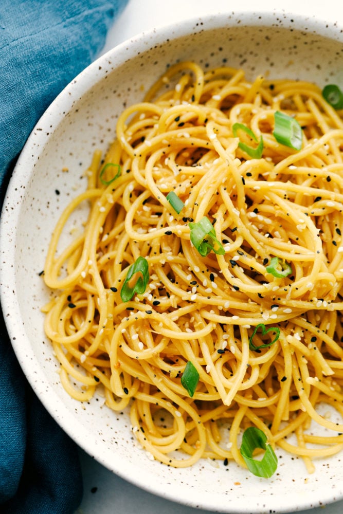 A quick and easy garlic sesame noodle recipe that is light and tasty! Add in vegetables and protein to enhance this oriental dish or keep it simple with a garlic sesame flavoring.ย Garlic sesame noodles in a bowl garnished with green onions.