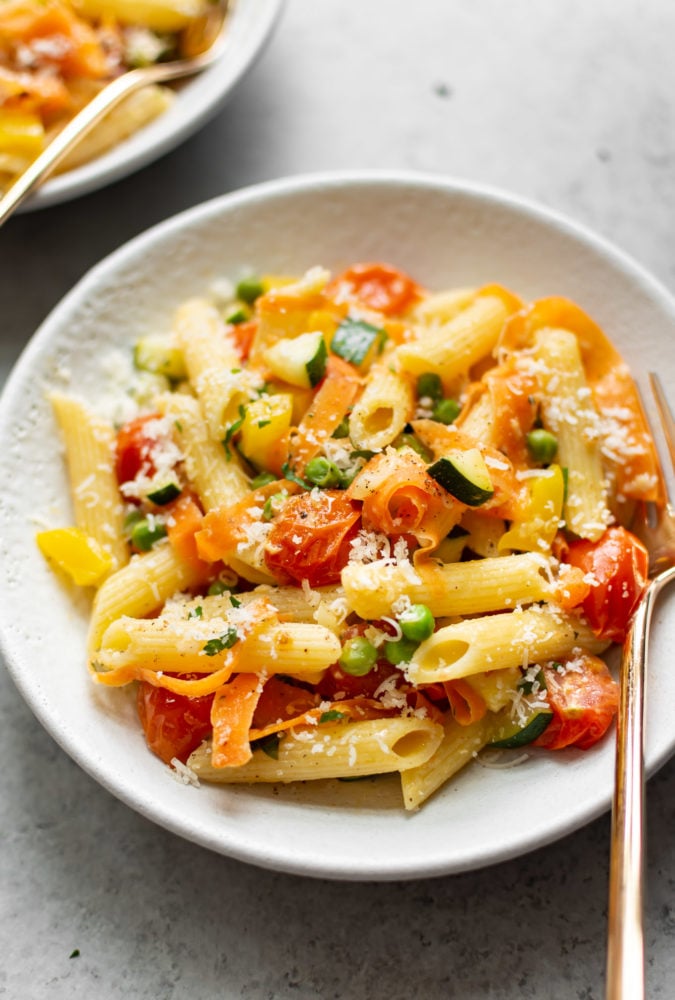 Pasta Primavera is a classic Italian American recipe that's loaded with spring vegetables. It has a light and fresh sauce and is the perfect break from heavier winter foods! Pasta primavera in a bowl with a fork.