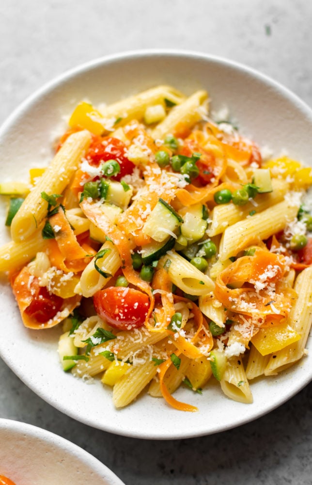 Pasta Primavera is a classic Italian American recipe that's loaded with spring vegetables. It has a light and fresh sauce and is the perfect break from heavier winter foods! Pasta primavera in a white bowl