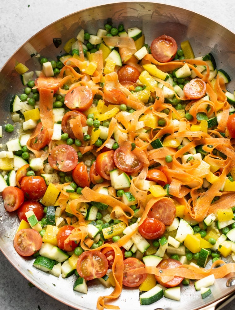 Pasta Primavera is a classic Italian American recipe that's loaded with spring vegetables. It has a light and fresh sauce and is the perfect break from heavier winter foods! Pasta primavera ina skillet cooking.