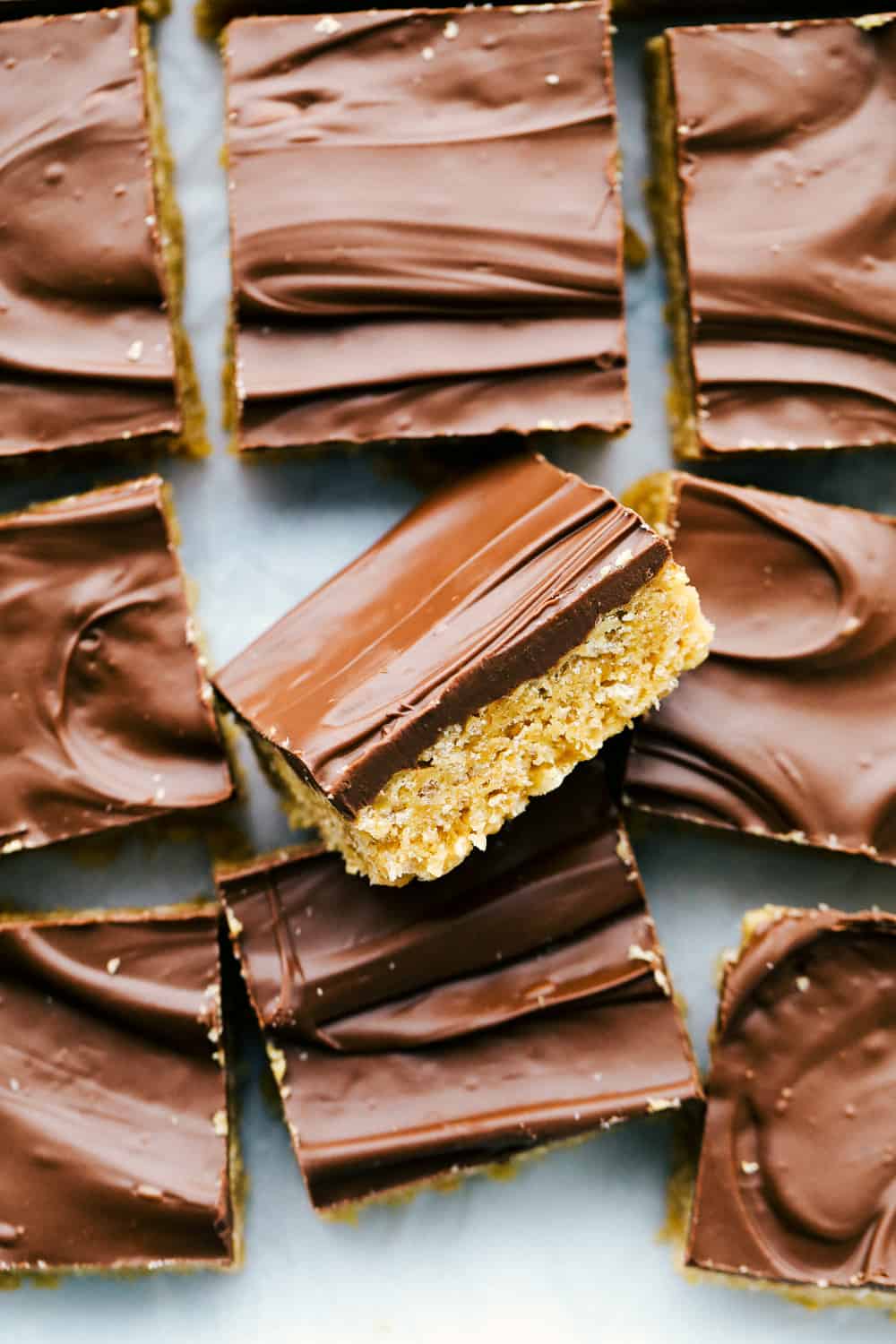 Scotcharoos are a perfect combination of butterscotch and peanut butter with a twist of a Rice Krispie crunch in the middle and a thick, rich chocolate layer that makes an irresistible treat. Sink your teeth in these ooey gooey bars! Scotcharoos cut up on a cutting board.