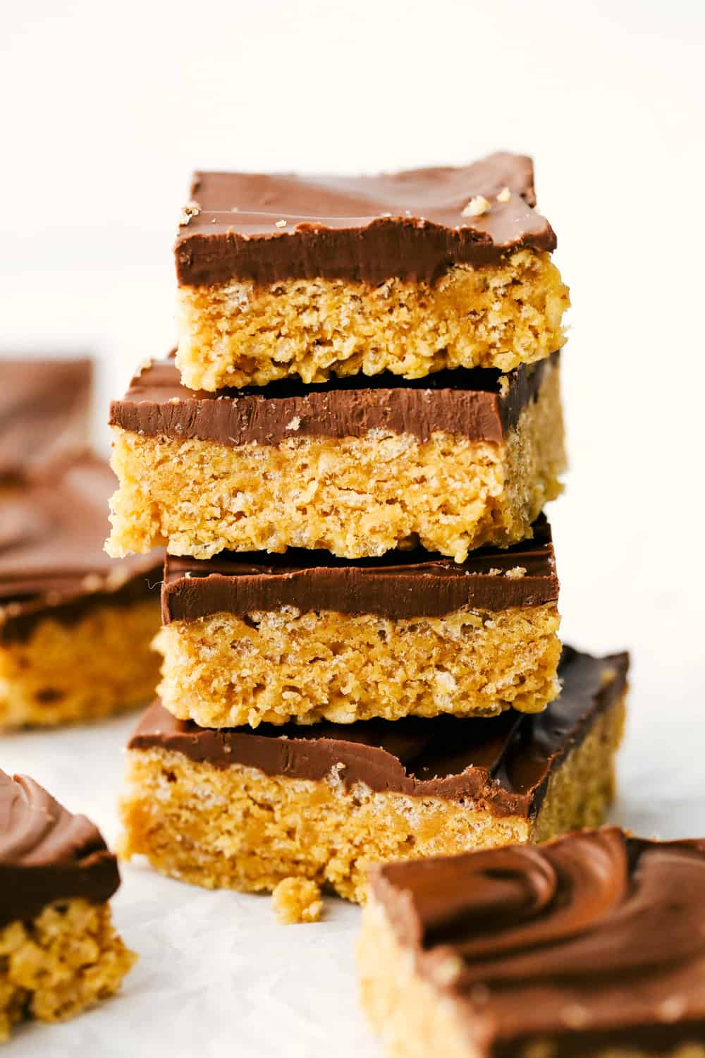 Scotcharoos are a perfect combination of butterscotch and peanut butter with a twist of a Rice Krispie crunch in the middle and a thick, rich chocolate layer that makes an irresistible treat. Sink your teeth in these ooey gooey bars! Scotcharoos stacked on top of each other.