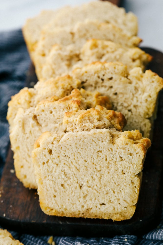 No yeast, No problem! This recipe is a light and fluffy buttery bread that is filled with a special ingredient that substitutes for yeast. You guessed it, beer! With this six ingredient recipe you will be sure to please your family with this homemade bread recipe! Buttery beer bread sliced up on a cutting board.