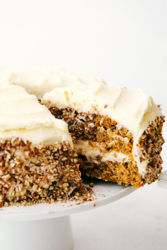 Carrot cake is moist, rich in flavor and melts in your mouth! This scrumptious dessert is what everyone will be raving about! Carrot cake sliced and being pulled away from the cake platter.