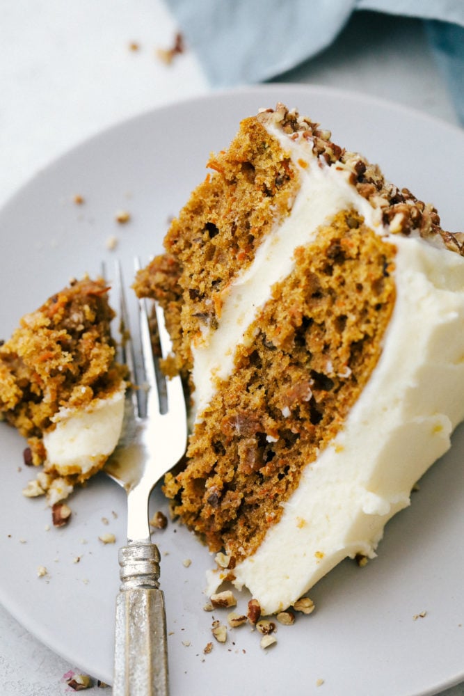 Carrot cake is moist, rich in flavor and melts in your mouth! This scrumptious dessert is what everyone will be raving about! Carrot cake on a plate with a fork cutting off a bite.