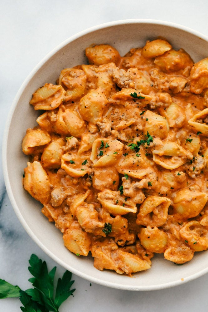 This cheesy beef and shells recipe is so simple to make with just a few ingredients straight out of your pantry, plus it all comes together in 20 minutes. Comforting, cheesy dinner that the whole family will love! Cheesy beef and shells in a bowl.