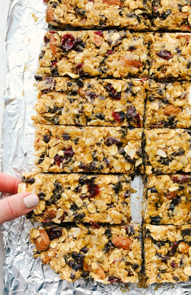 Easy to make chewy granola bars that are homemade filled with regular oats, dried cranberries, salty almonds, mini dark chocolate chips all combined with a sweet honey and a peanut butter flavoring. Snack time just got easier with these tasty bars!ย Granola bars cut up into long slices.