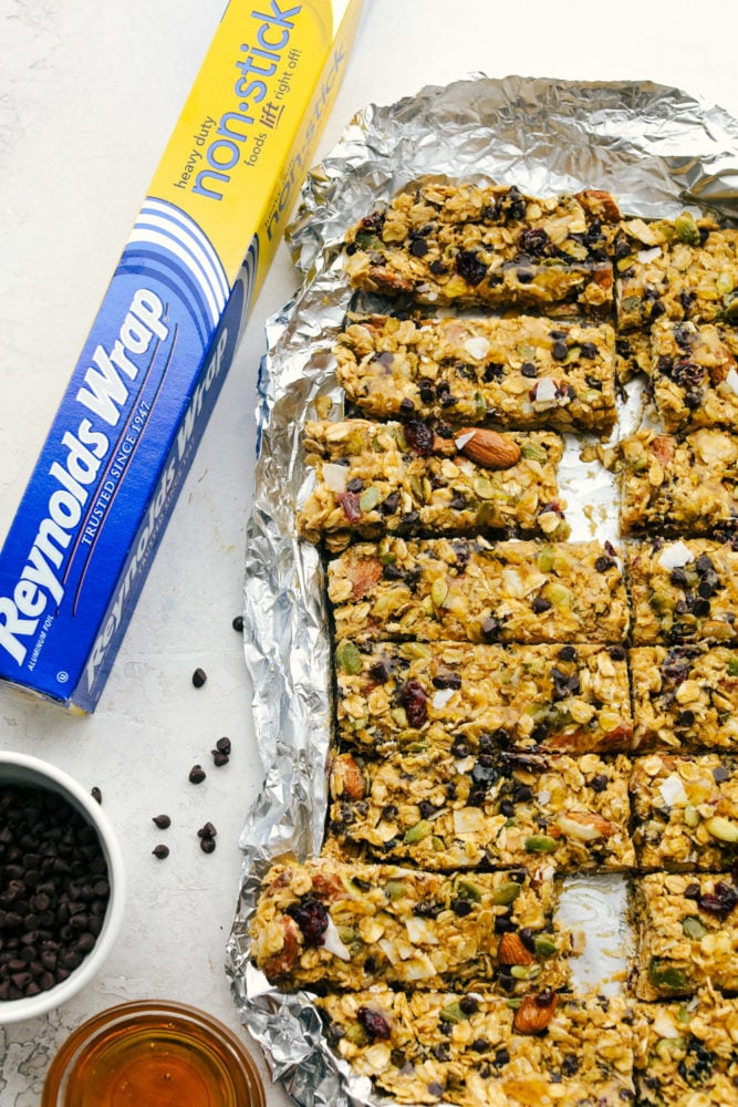 Easy to make chewy granola bars that are homemade filled with regular oats, dried cranberries, salty almonds, mini dark chocolate chips all combined with a sweet honey and a peanut butter flavoring. Snack time just got easier with these tasty bars!ย Granola bars ono nonstick aluminum foil.
