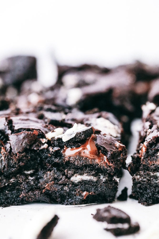 These brownies are layered with a rich chocolatey batter with Oreos in the middle creating a soft, gooey center with chunks of chocolate and Oreo pieces in every bite. Oreo brownies make everyday a great day! Oreo brownies photo of the side of the oreo with chunks of oreo showing.