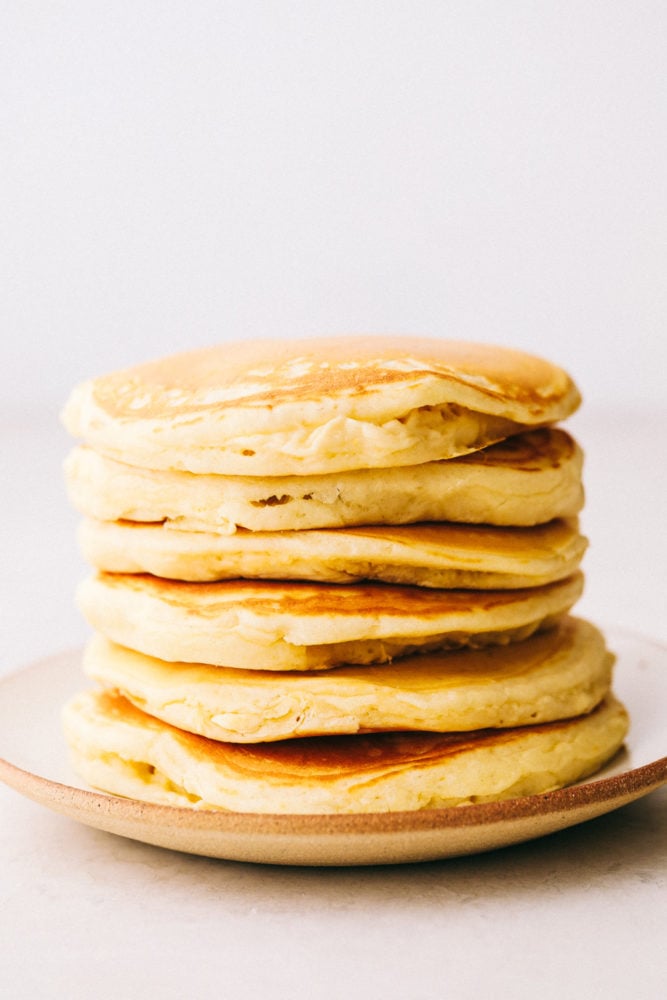 Grandma's homemade fluffy pancakes are the ultimate comfort breakfast! They're light and airy, yet satisfyingly filling, making them the perfect morning treat. Fluffy pancakes stacked on top of each other.