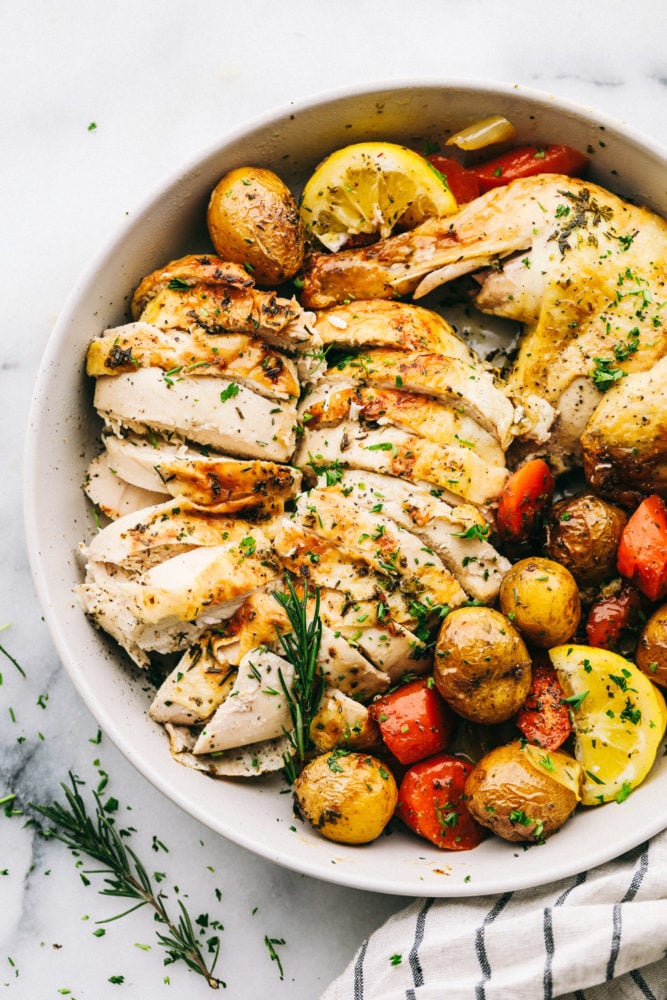 Garlic roasted chicken with vegetables is a whole chicken rubbed with an herb butter then stuffed with a mixture of seasonings. Roasted in a large skillet combined with fresh, flavorful vegetables!ย Garlic roasted chicken with vegetable in a bowl ready to serve.