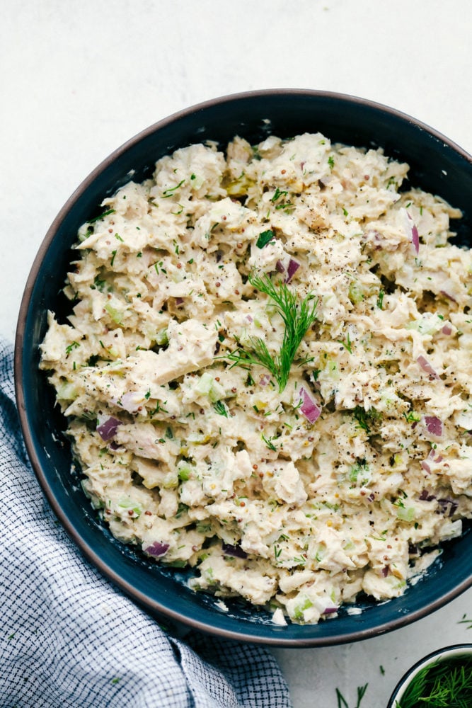 This tuna salad is a classic favorite that mixes up well and tastes rich and creamy with slices of crisp celery and red onions for that added crunch. All comes together quickly and easily with pantry ingredients! Tuna salad mixed together in a black bowl.