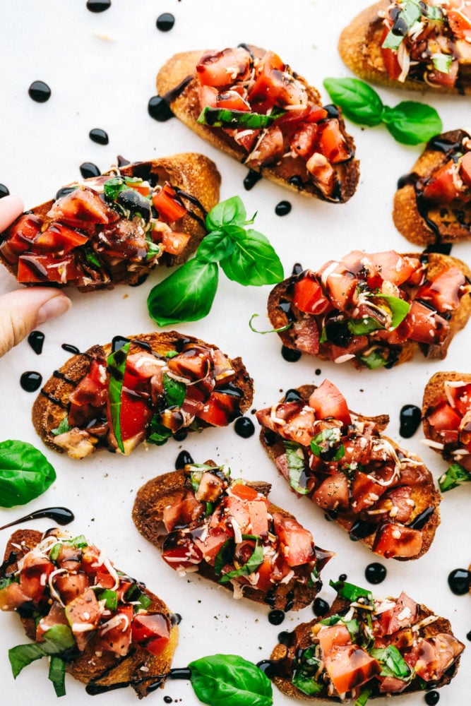 This bruschetta is easy to make with fresh, ripe Roma tomatoes, shredded mozzarella cheese and drizzled with balsamic vinaigrette over top of a French baguette. Bruschetta comes together quickly and easily!ย Bruschetta toast on a white countertop garnished with cilantro.