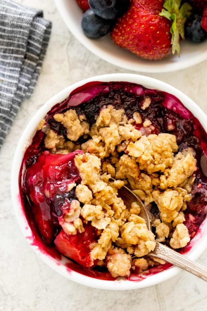 Mixed berry crisp is a colorful combination of fruit with a crunchy oat topping. These smaller individual portions baked in a ramekin make it easy to serve. The warm dessert tastes incredible topped with whipped cream or ice cream. Mixed Berry Crisp