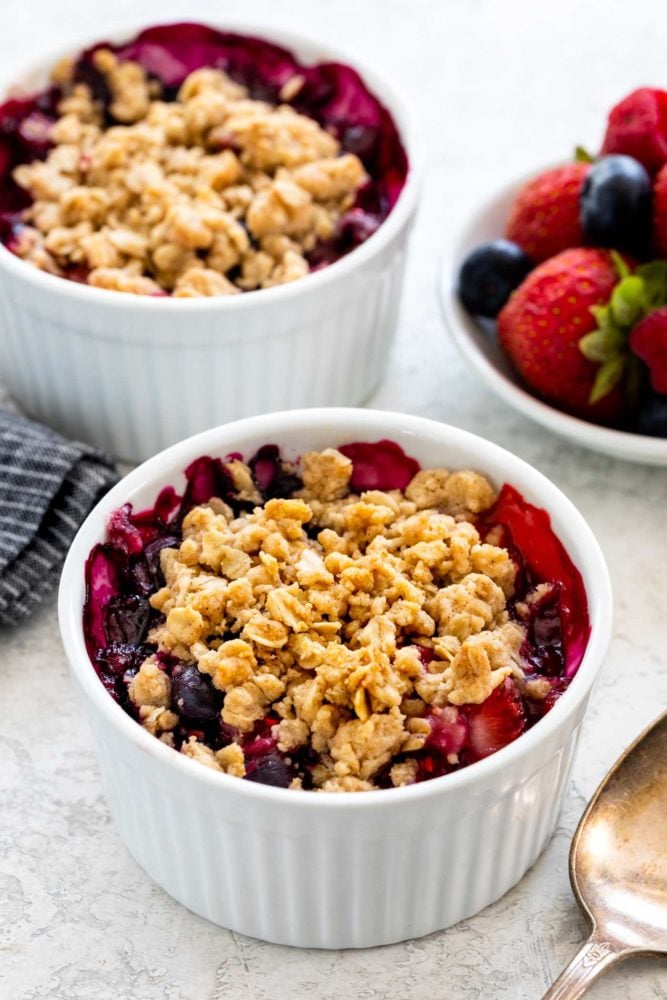 Mixed berry crisp is a colorful combination of fruit with a crunchy oat topping. These smaller individual portions baked in a ramekin make it easy to serve. The warm dessert tastes incredible topped with whipped cream or ice cream. Mixed fruit berry crisp with oat topping