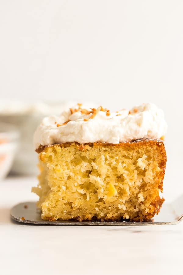 This Pineapple Cake recipe is made from scratch with crushed pineapple and topped with cream cheese whipped cream for a light but decadent treat! #pineapple #cake #baking #dessert pineapple cake piece