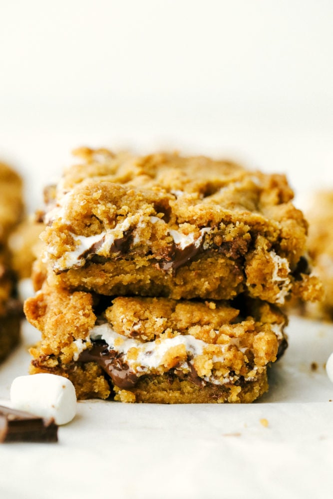 Ooey Gooey S'mores Bars are a delicious treat inspired by campfire s'mores with melty marshmallow, a buttery graham cracker crust, and a rich-sweet chocolate.ย These satisfying and easy to make bars are irresistible! Sโmores bars stacked on top of each other.