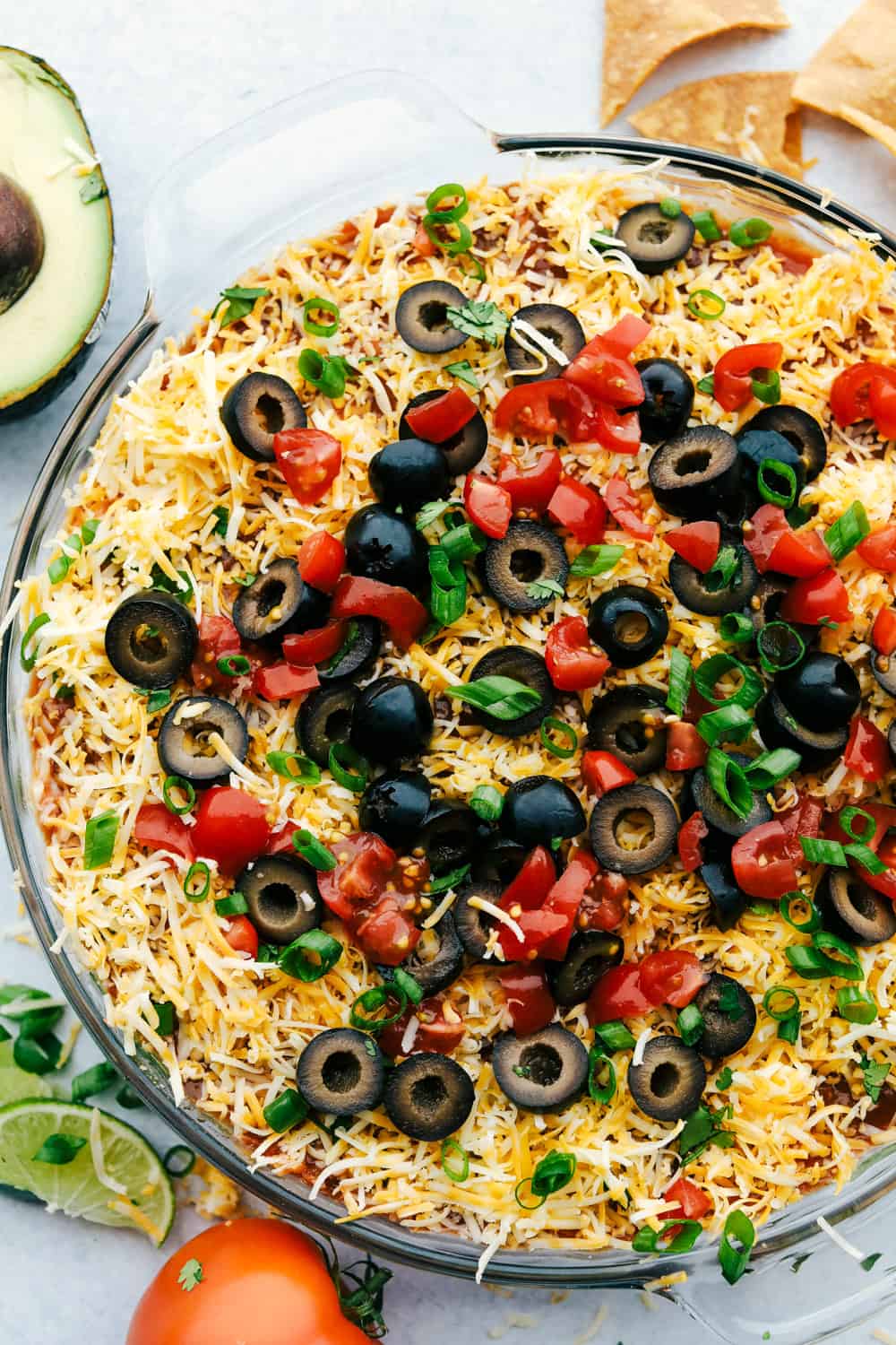 Awesome 7 Layer Dip is an addicting creamy dip that includes all your favorites, like guacamole, refried beans, and sour cream! You will be amazed at how simple it is to put together such an incredibly delicious dip! Overhead shot of 7 layer dip.