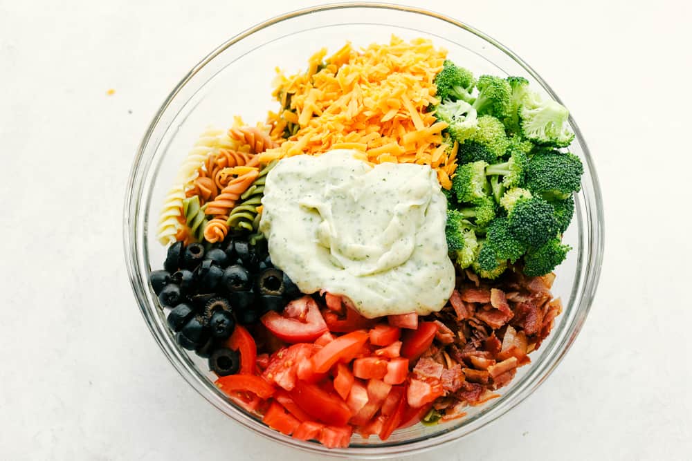 This bacon ranch pasta salad is filled with colorful veggies and perfectly contrasting textures and flavors! Every bite is so satisfying it will be an incredible hit with anyone lucky enough to enjoy it! Bacon Ranch Pasta Salad ingredients in a clear bowl.