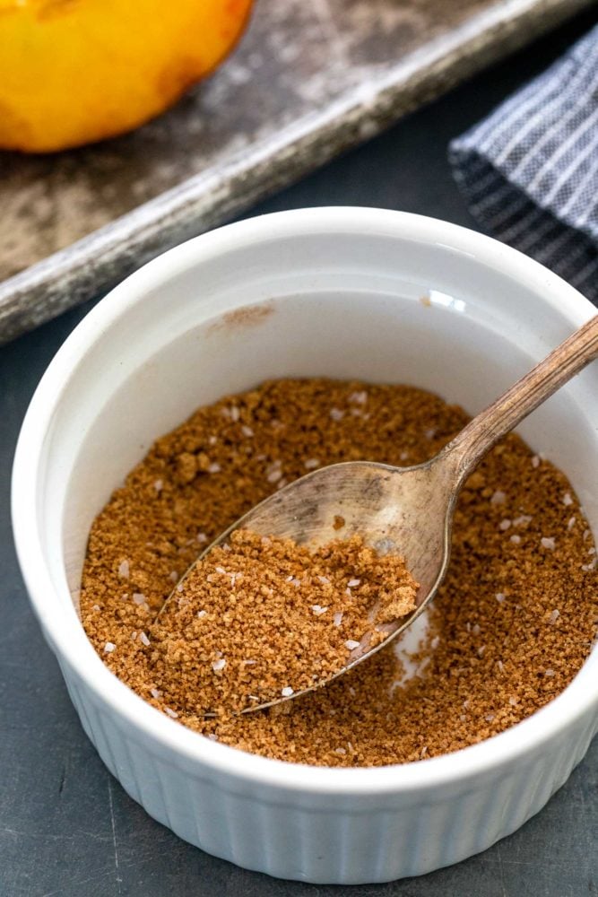 Brown sugar grilled peaches are a summertime delight. Ripe peaches are lightly charred on the barbecue then sprinkled with a sweet spiced topping that transforms into a glaze. Perfect as a quick dessert or add it to a fresh salad.ย brown sugar and spices in a white ramekin with a silver spoon.