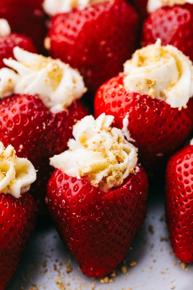Cheesecake stuffed strawberries are the perfect party treat filled with a creamy and smooth cream cheese filling. Topped with a graham cracker crumb, they are juicy, tangy, and sweet all at the same time. This easy and quick dessert is unbelievably delicious and impossible to resist! Close up on cheesecake stuffed strawberries.
