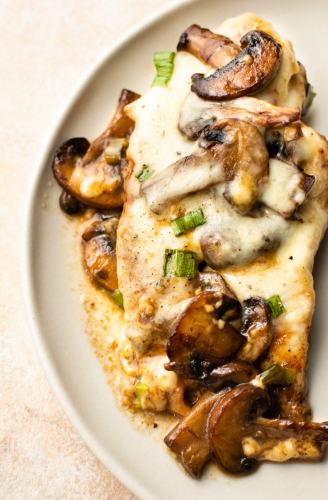 Chicken Lombardy is an insanely delicious cheesy version of Chicken Marsala baked to perfection with mozzarella and scallions. Ready in about 30 minutes! Chicken Lombardy close-up on a plate