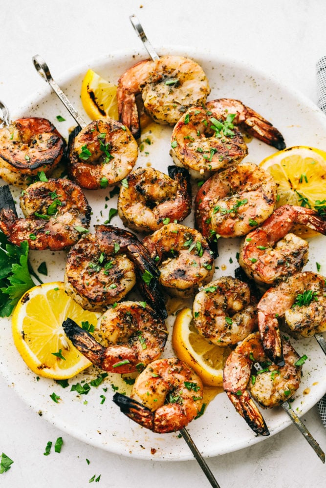 The BEST Grilled Shrimp is the perfect weeknight meal because it is super quick, full of flavor, and so easy to make!ย Everyone will absolutely love and devour it!! Grilled shrimp on a white plate.