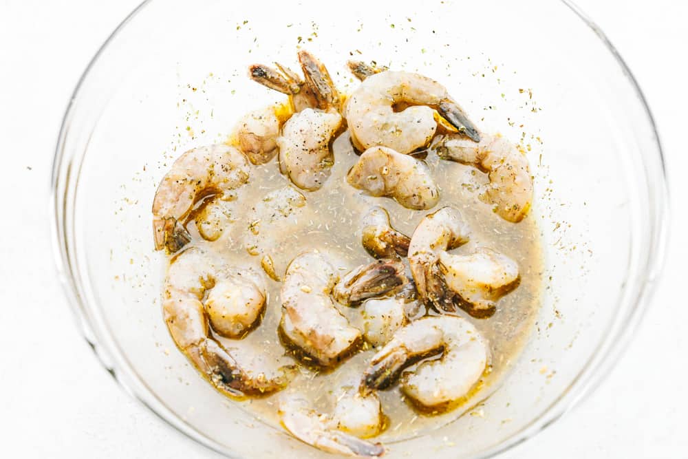The BEST Grilled Shrimp is the perfect weeknight meal because it is super quick, full of flavor, and so easy to make!ย Everyone will absolutely love and devour it!! Grilled shrimp marinating in a clear bowl.