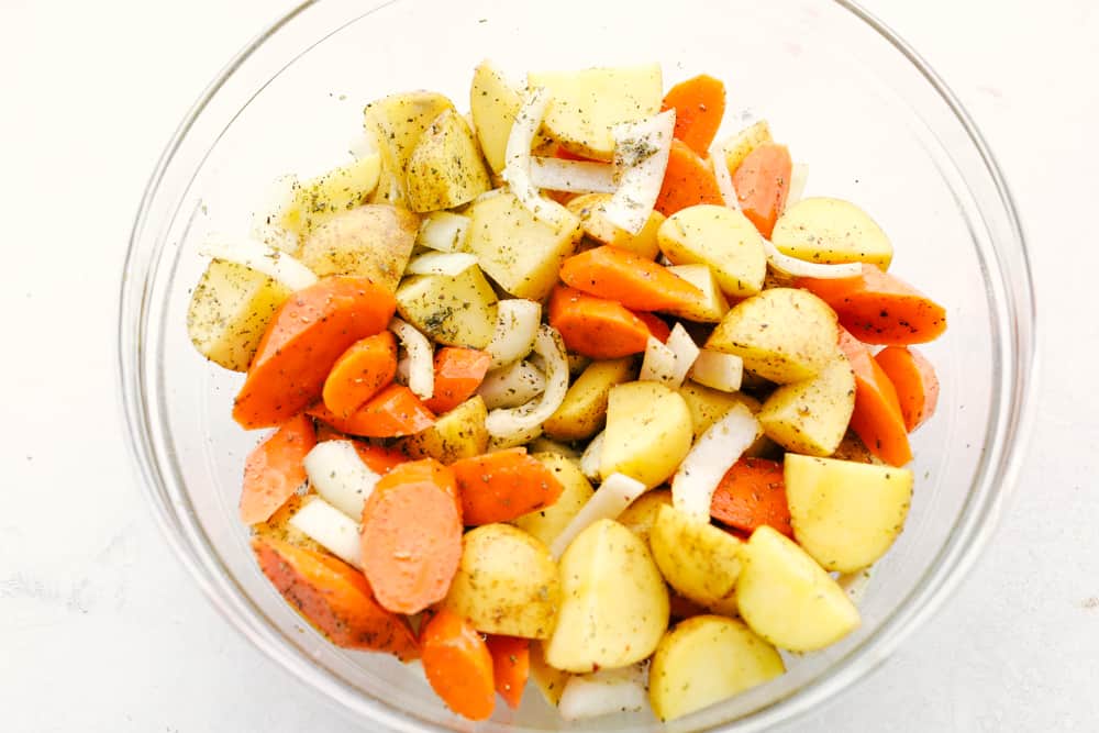 You know those nights when everyoneโs hungry and youโre one eye twitch away from serving cereal? My easy Hobo Dinner Foil Packets, packed with hearty veggies and juicy beef, are the answer! Bowl of seasoned cut up veggies.