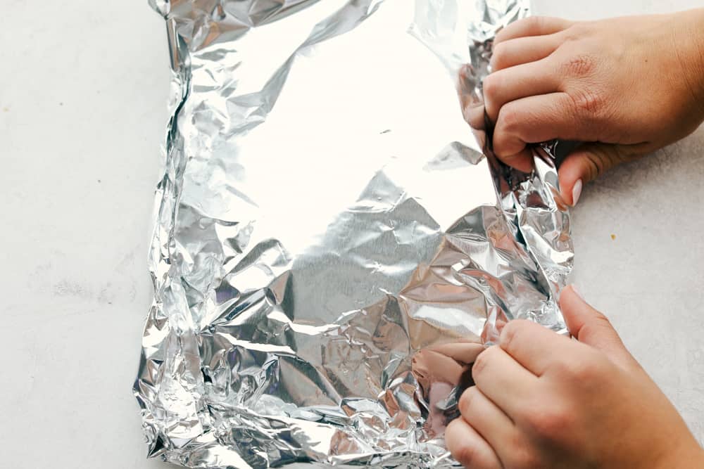 You know those nights when everyoneโs hungry and youโre one eye twitch away from serving cereal? My easy Hobo Dinner Foil Packets, packed with hearty veggies and juicy beef, are the answer! Someone rolling up a foil packet.
