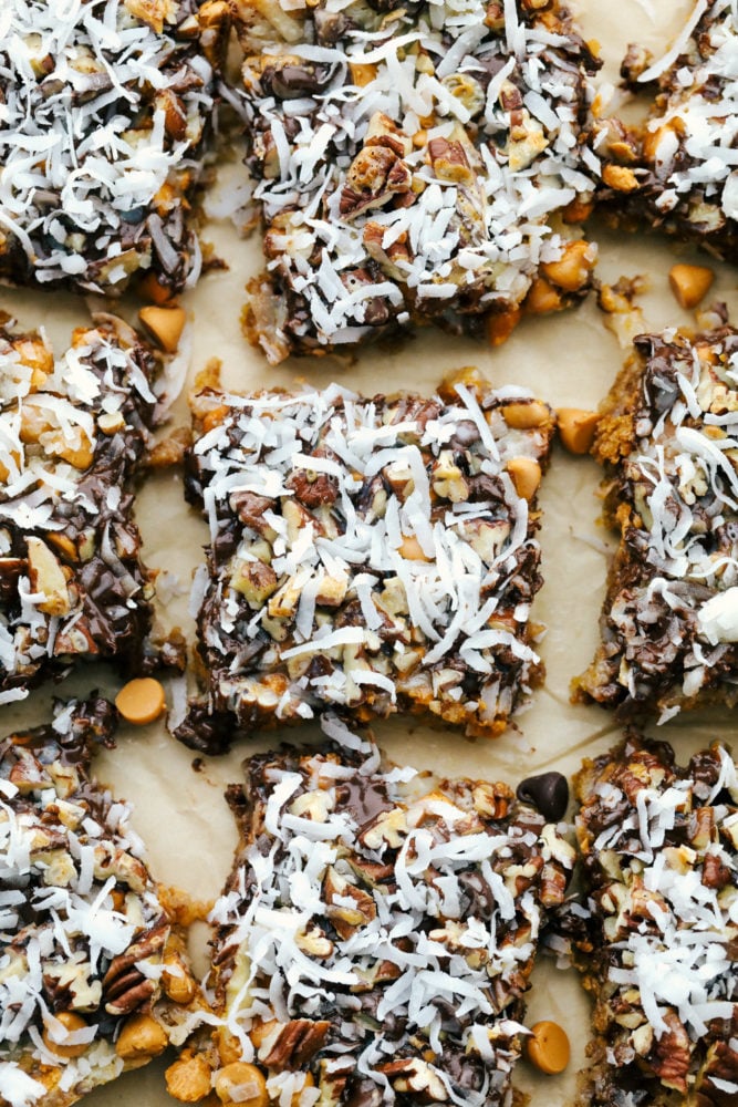 7 Layer Magic Bars are loaded with layers of rich flavors from coconut, pecans, butterscotch, and chocolate. You will be amazed how easy it is to create a bar this delicious where every single bite is ooey gooey perfection! 7 layer bars cut into squares.