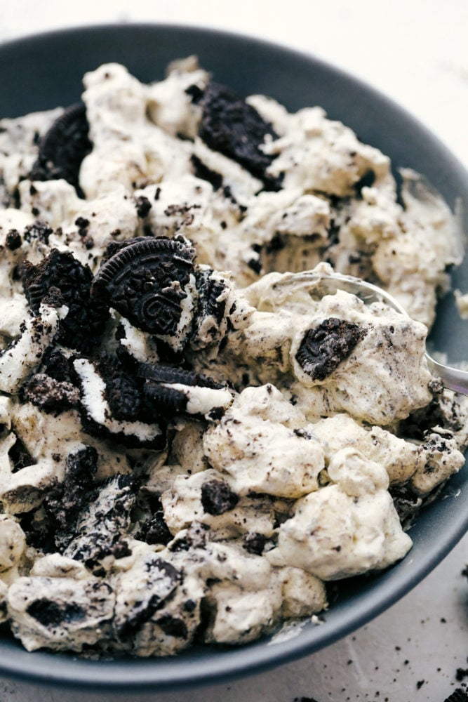 Oreo fluff dessert salad has the perfect sweet cream and marshmallow fluff with pops of crunchy Oreo cookies throughout. This soft and sweet mixture is a hugely popular dessert you will love at first bite! Oreo fluff dessert in a bowl.