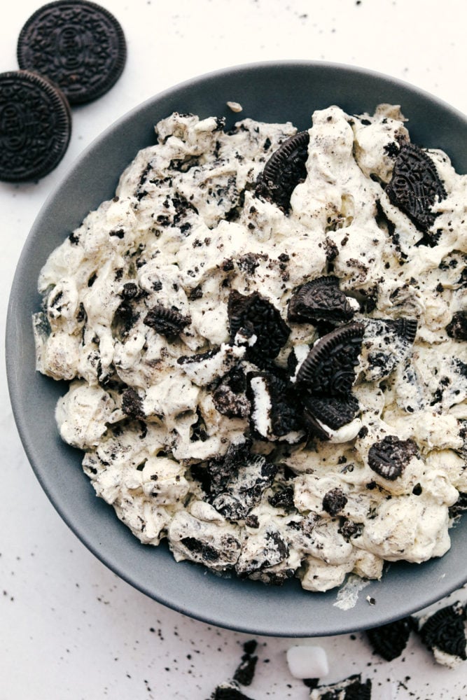 Oreo fluff dessert salad has the perfect sweet cream and marshmallow fluff with pops of crunchy Oreo cookies throughout. This soft and sweet mixture is a hugely popular dessert you will love at first bite! Oreo fluff on a black plate.