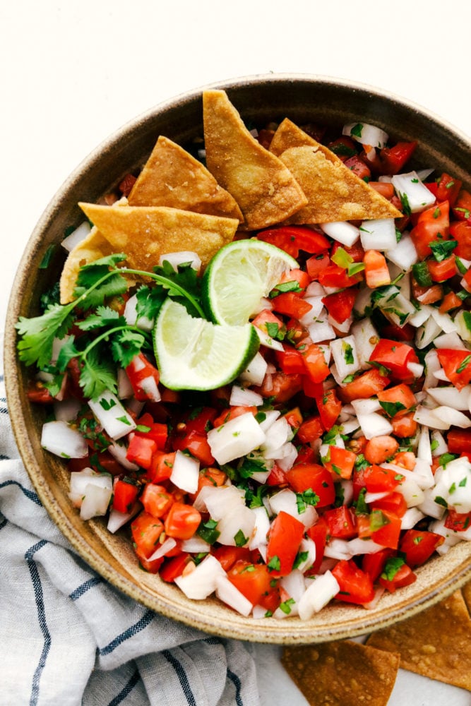 Pico de Gallo is a made from scratch salsa that is loaded with bold flavors from jalapeno, lime, cilantro, and juicy chunks of tomato and onion. One dip will certainly not be enough and you will be scraping the bottom of the bowl in no time! Bowl of pico de gallo.