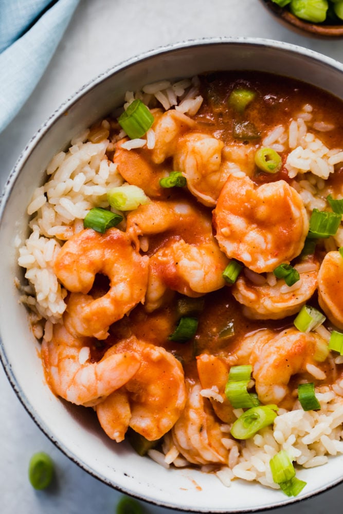 Creole Shrimp Étouffée is a classic southern stew is full of tender shrimp, the "Holy Trinity" of veggies, and flavored with a decadent golden roux. This stew has a subtle heat thanks to seasoning, but served over rice is the ultimate in Louisiana comfort food! Creole shrimp étouffée over top rice in a bowl topped with scallions.