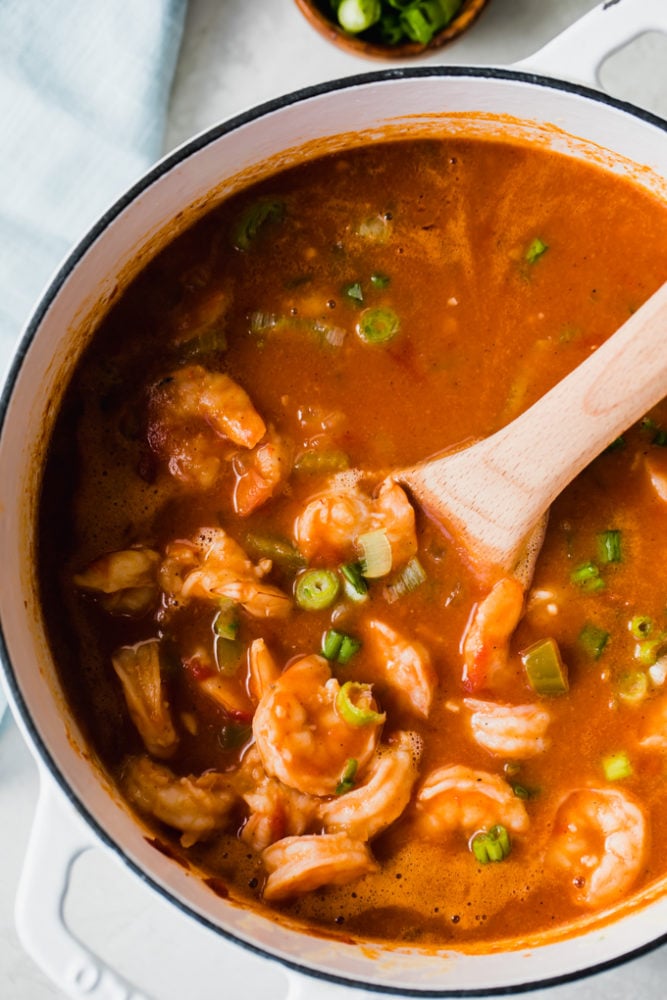 Creole Shrimp Étouffée is a classic southern stew is full of tender shrimp, the "Holy Trinity" of veggies, and flavored with a decadent golden roux. This stew has a subtle heat thanks to seasoning, but served over rice is the ultimate in Louisiana comfort food! Creole shrimp étouffée in a large pot being stirred with a wooden spoon.