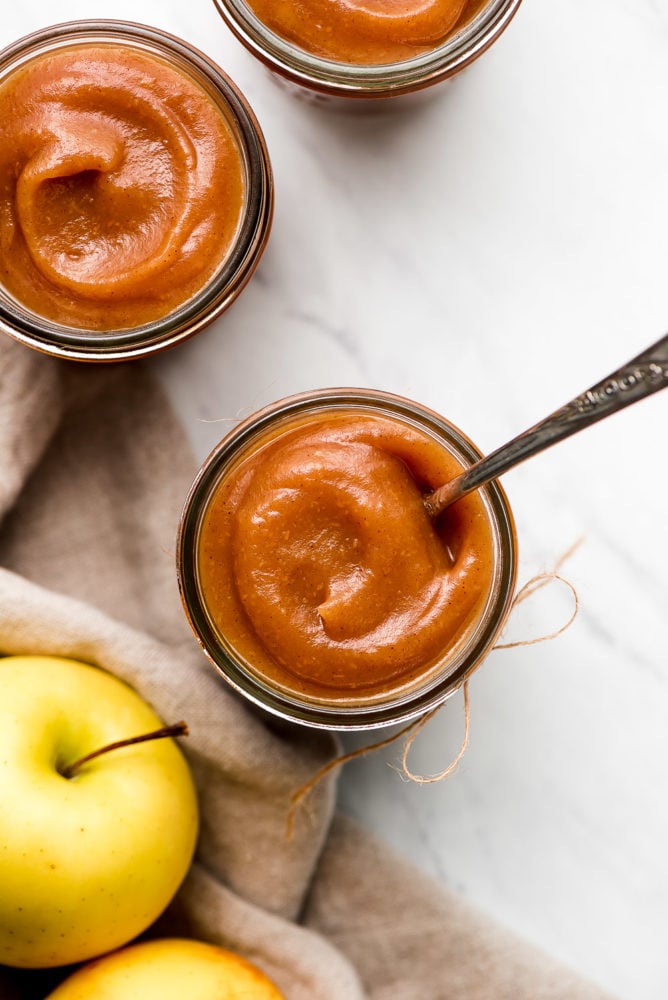 Apple Butter is a sweet velvety concentrated apple spread that youโll want to put on everything. It requires just a few ingredients and a little bit of patience to make this yummy jam like condiment. Top view of jars of thick apple butter.