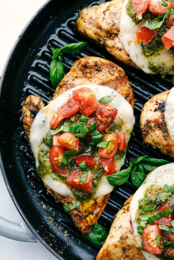 Chicken Margherita is tender and flavor packed grilled chicken that is smothered with mozzarella, pesto, and juicy cherry tomatoes. Liven up dinnertime with this restaurant quality meal that's quick and easy to make at home! Chicken Margherita in a skillet.